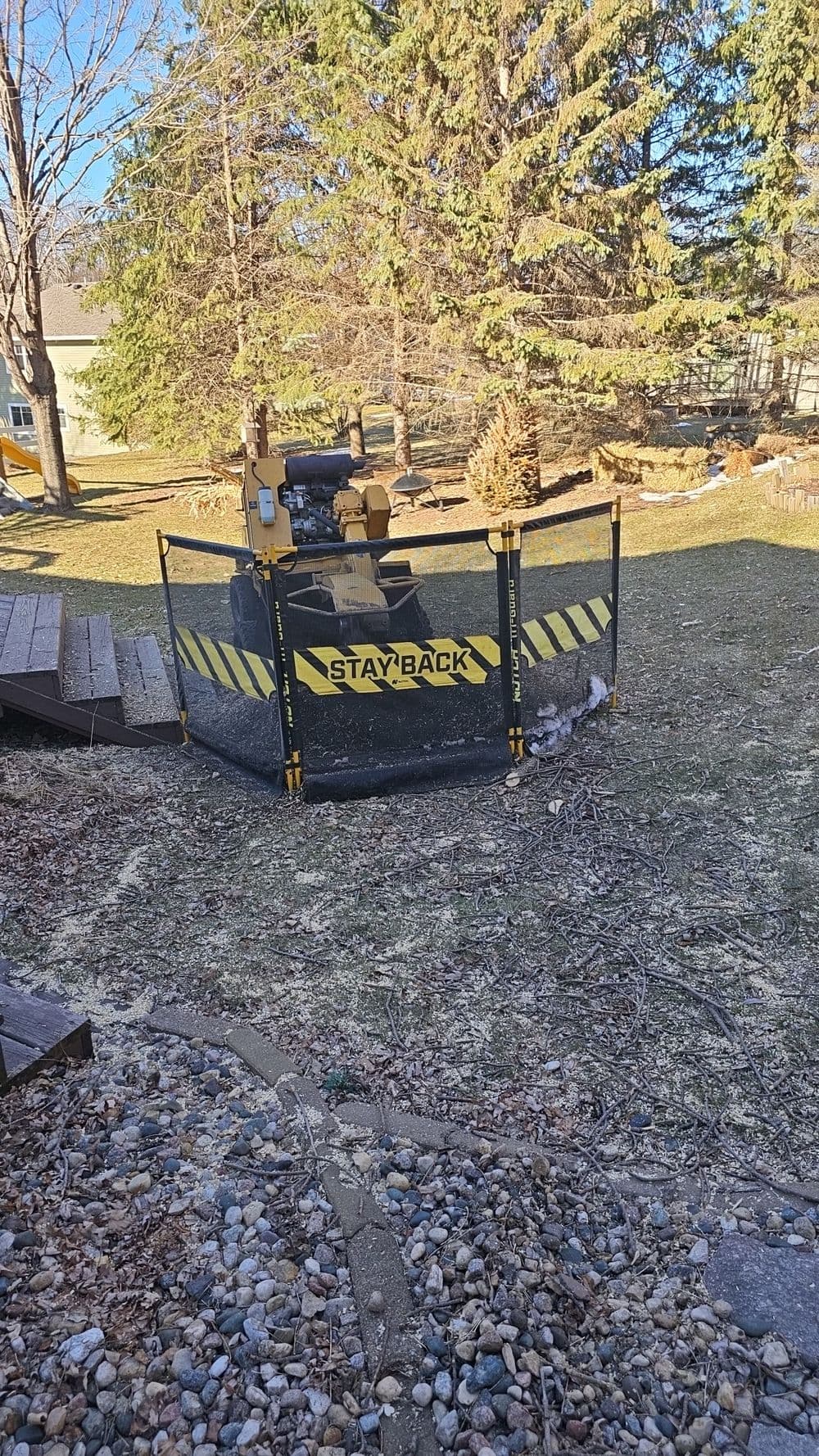 Construction area safety fence with "STAY BACK" sign in a residential yard.