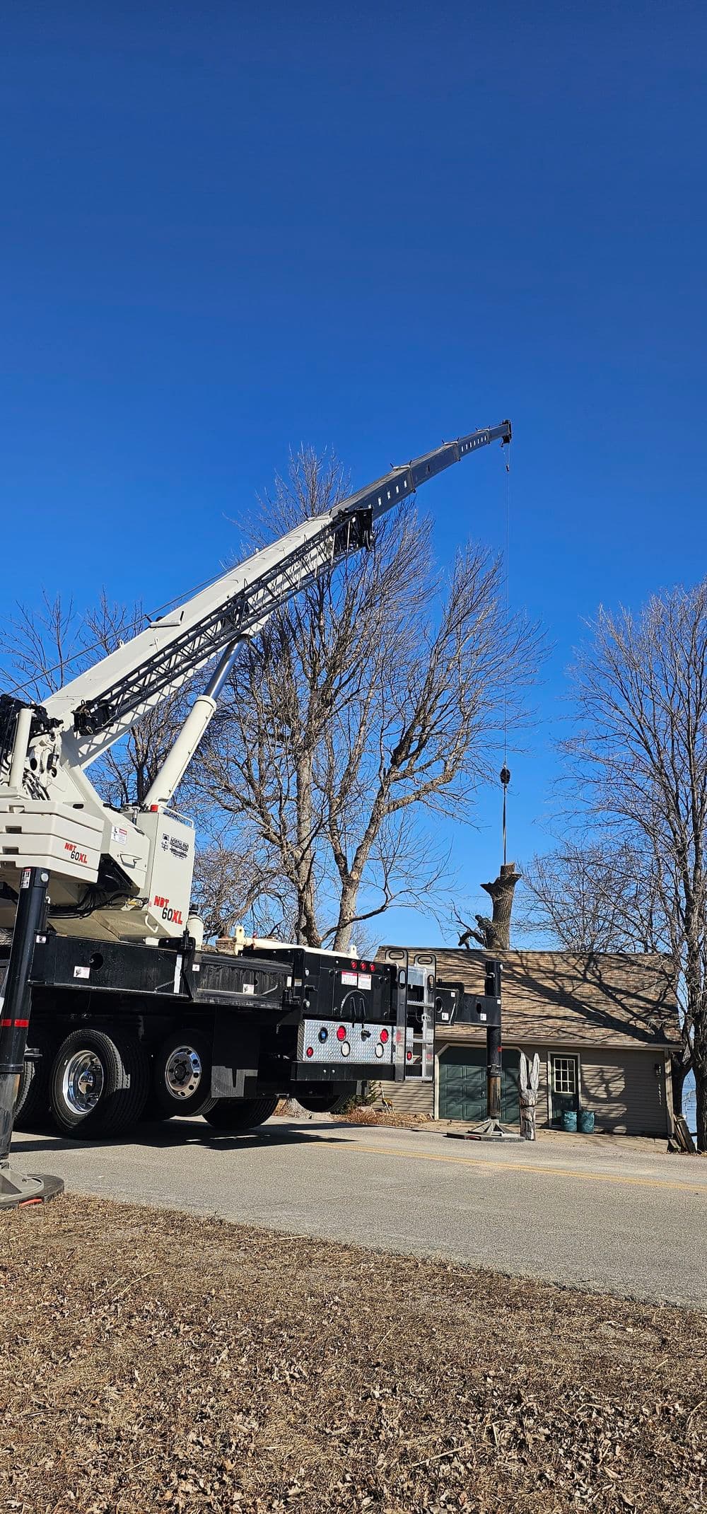 Crane lifting a sculpture outdoors with clear blue skies in the background.