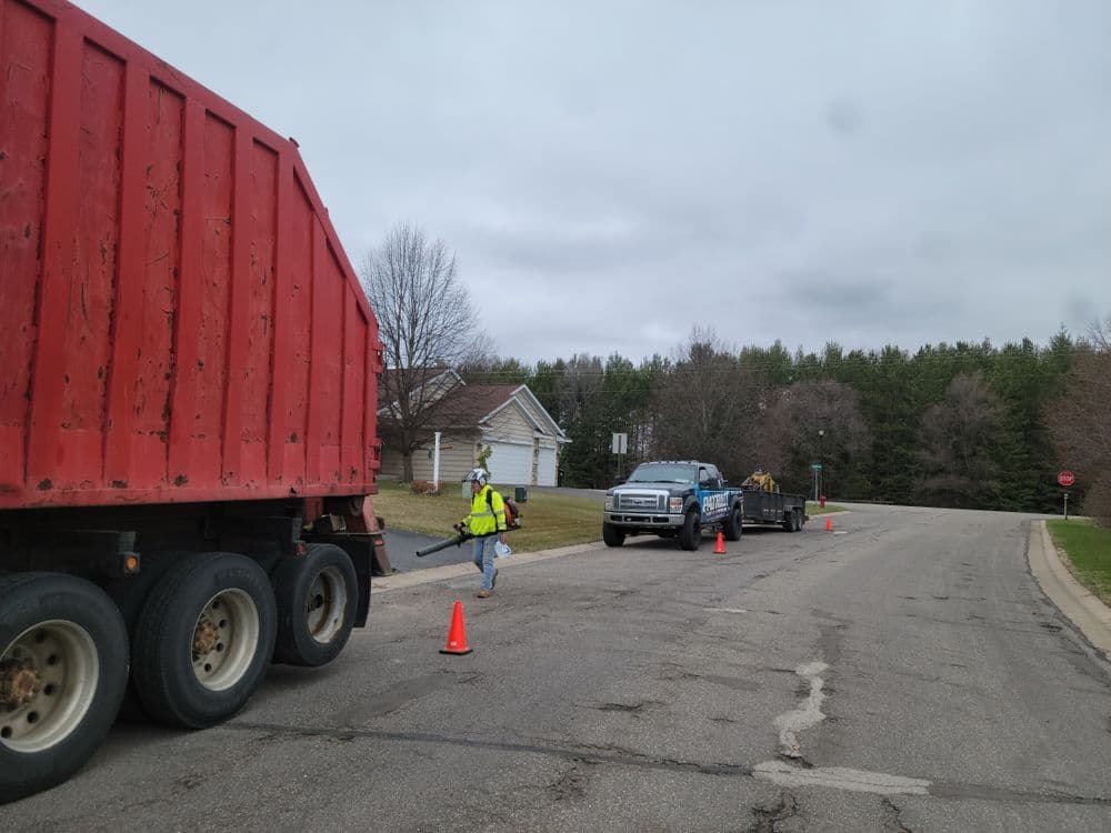 Construction worker directing traffic near red dump truck on residential street.