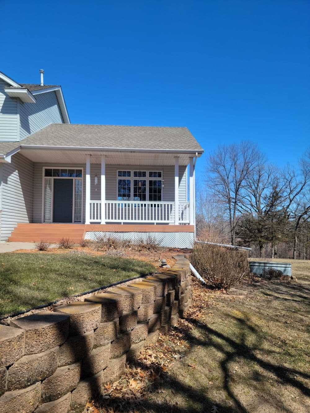 Modern house with porch and landscaped yard under a clear blue sky.